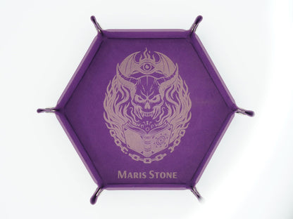 A purple hexagonal display stand with four metal legs and a central printed design of a skull wearing a crescent moon and eye helmet, with the text 'MARIS STONE' at the bottom.